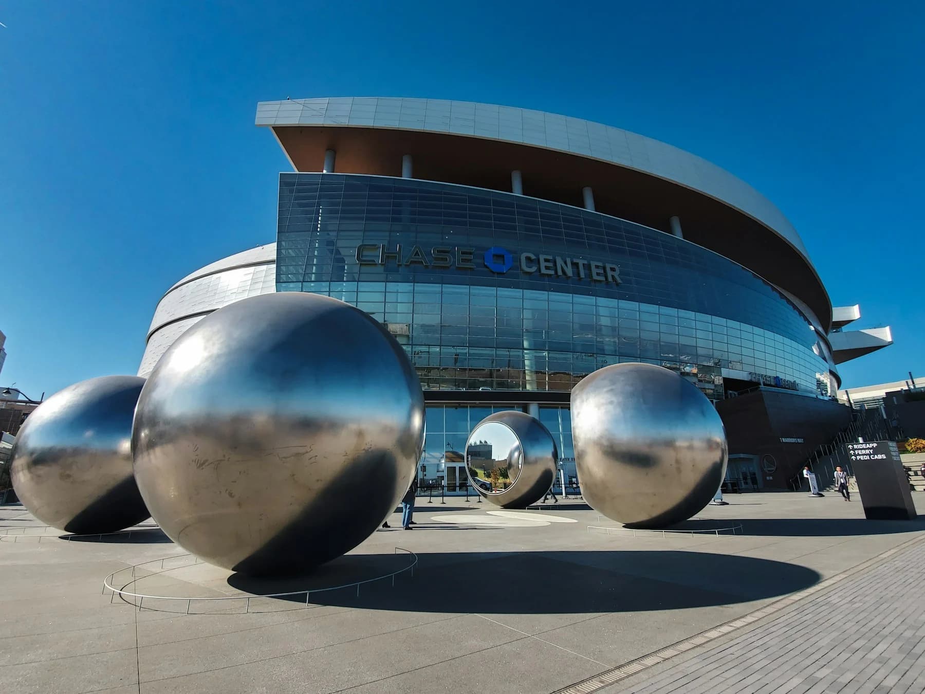 Chase Center’s curved exterior and plaza under a blue San Francisco sky