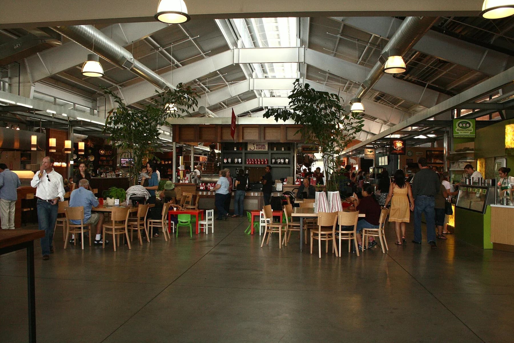 Interior de Oxbow Public Market, con puestos de comida y comensales bajo los tragaluces.