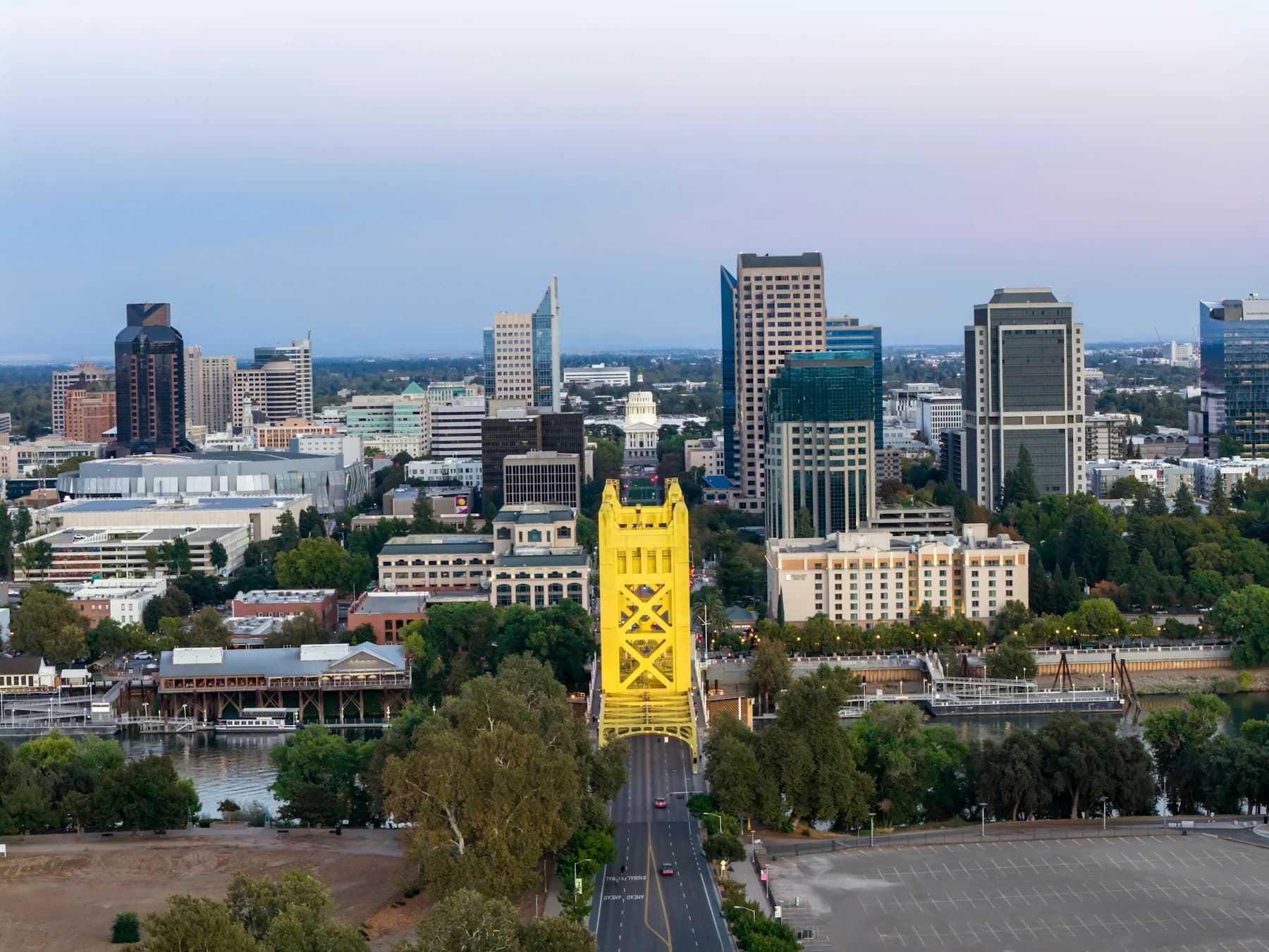 Sacramento’s yellow Tower Bridge leading toward the downtown skyline at dusk